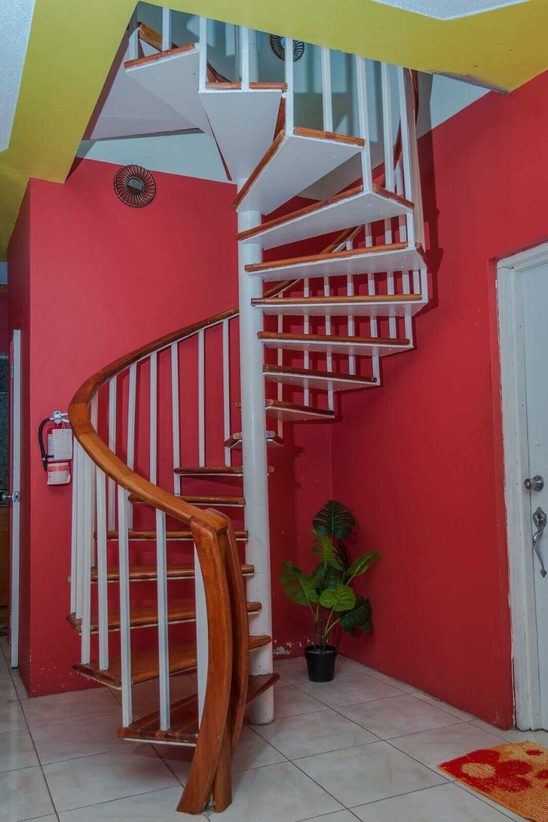 A spiral staircase with wooden handrails and white steps, leading to an upper floor.