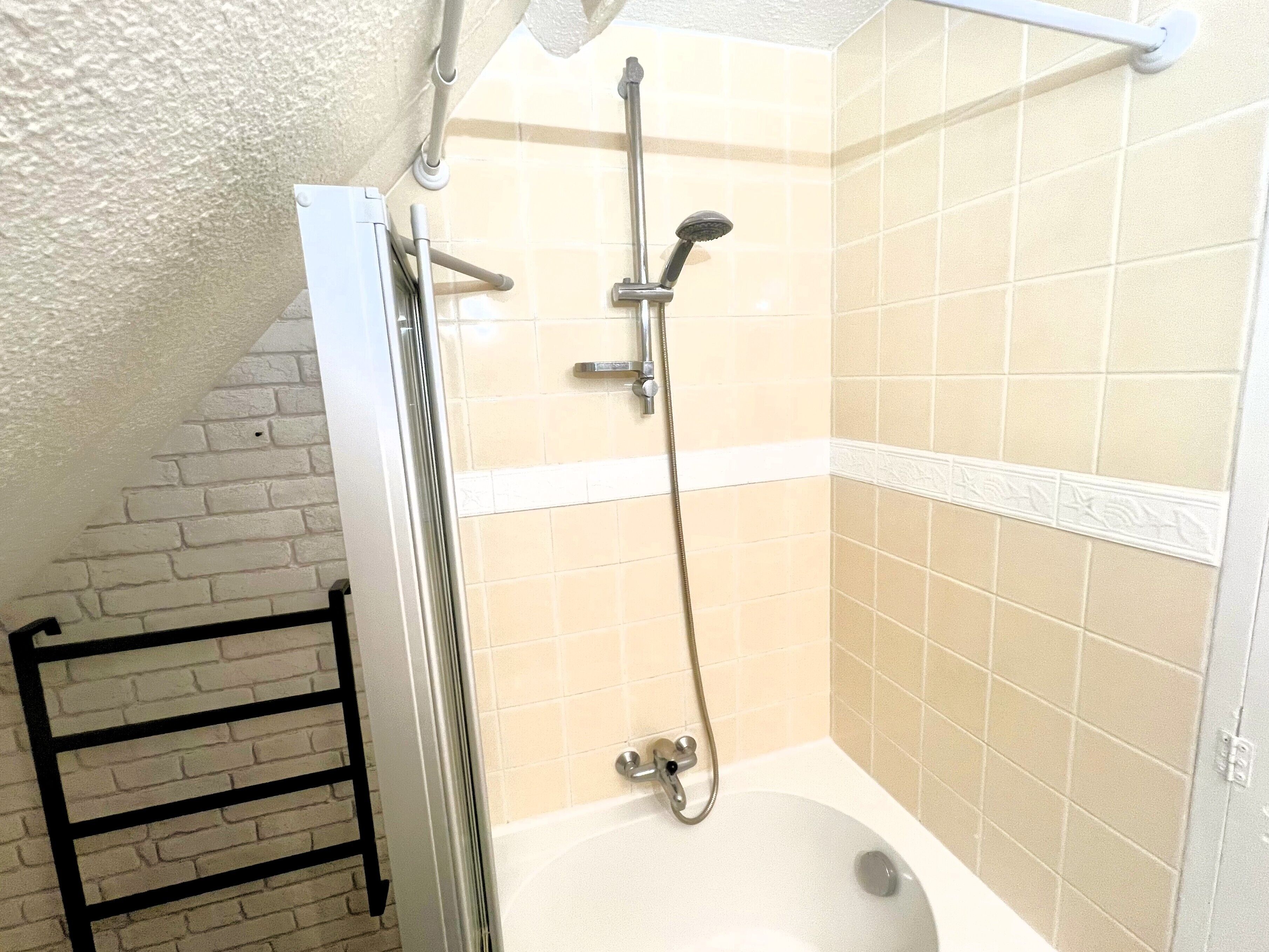 Une petite salle de bain avec une douche, une baignoire et un porte-serviettes.