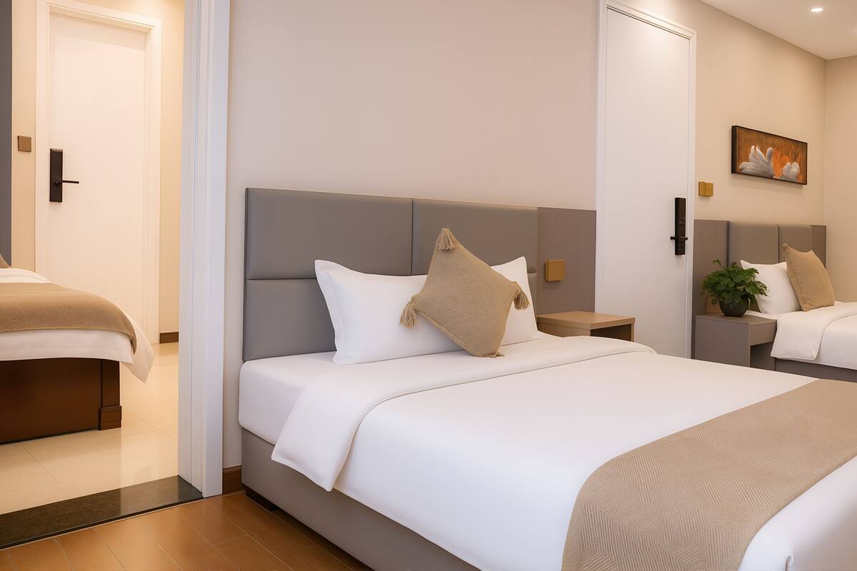 Et hotelværelse med to senge, en neutral farvesammensætning og et moderne design.