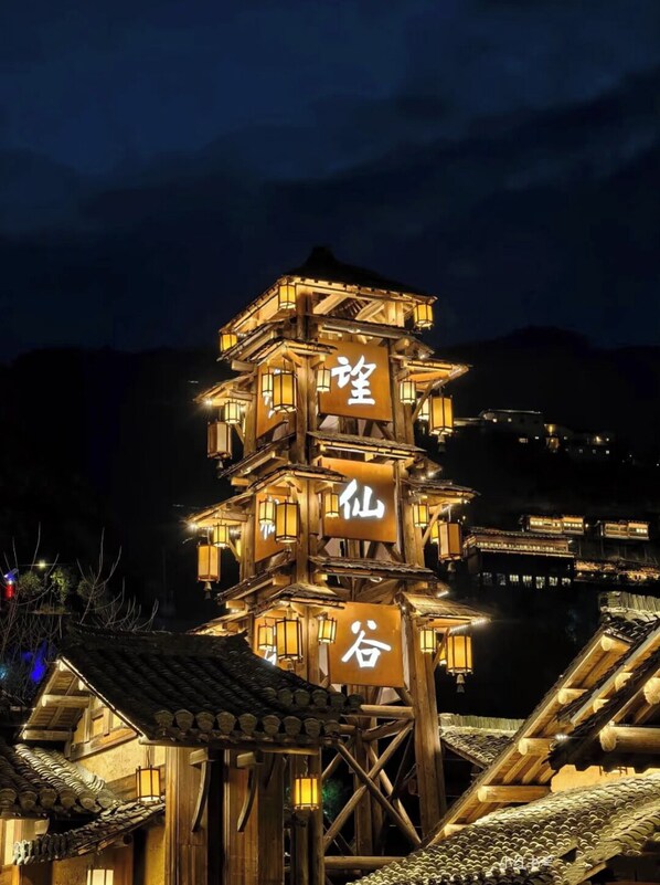 A multi-tiered wooden structure with illuminated signs, likely a traditional building or tower in a rural setting. - Wangxian Valley Morning Wind B&B - Wangxian Valley Scenic Area (Shangrao)