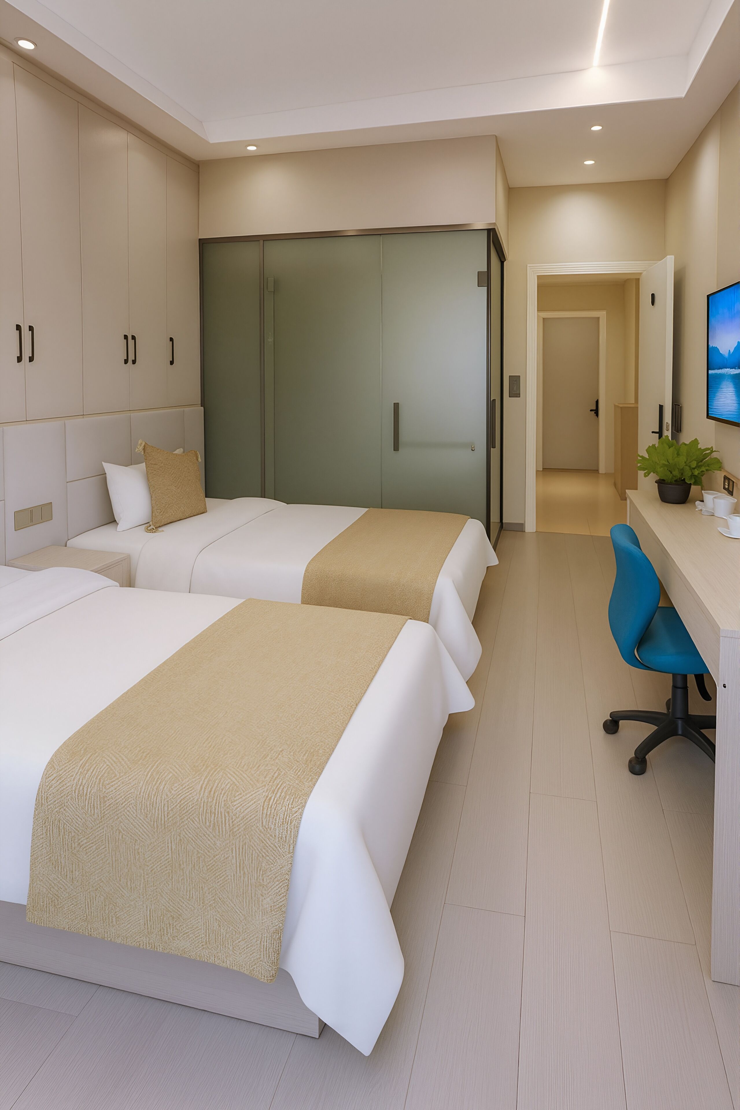 A hotel room with two beds, a desk, a chair, a TV, and a plant.
