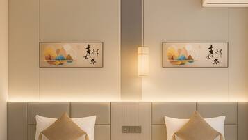 A hotel room with two beds, each with a beige pillow and a white bedspread. There are wall-mounted artworks depicting nature scenes.