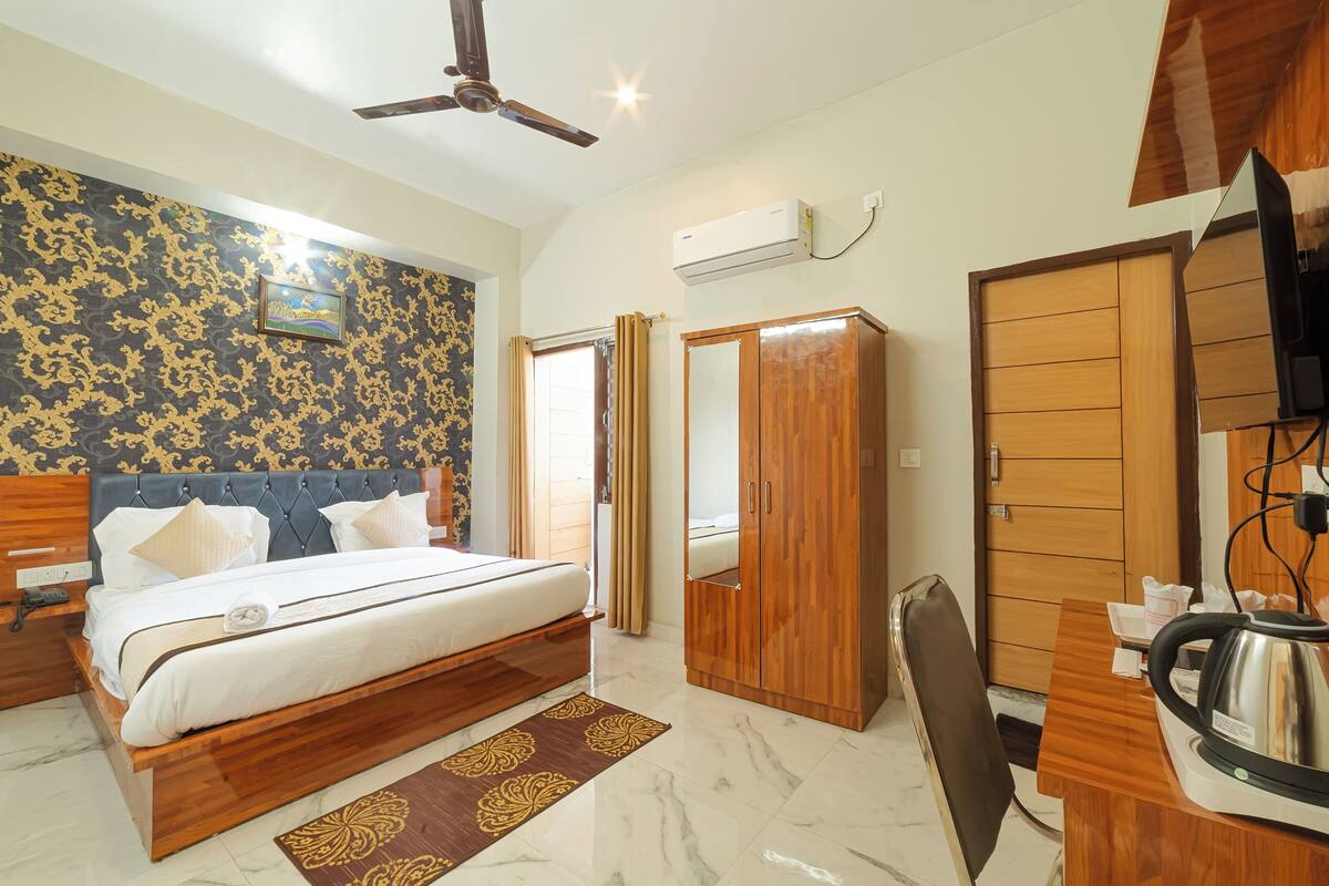 Quarto de hotel com cama, guarda-roupa, escrivaninha e ventoinha no teto.