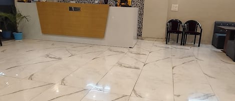 A reception area with a marble floor, a reception desk, and a wall decorated with various items.