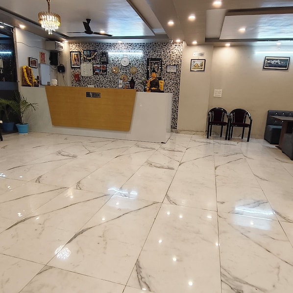 Un espace d’accueil doté d’un sol en marbre, d’un comptoir de réception et d’un mur décoré de divers objets.