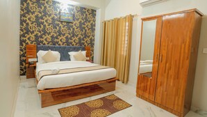 A hotel room with a bed, wooden wardrobe, and a mirror. - Hotel Rudra (Rishikesh)
