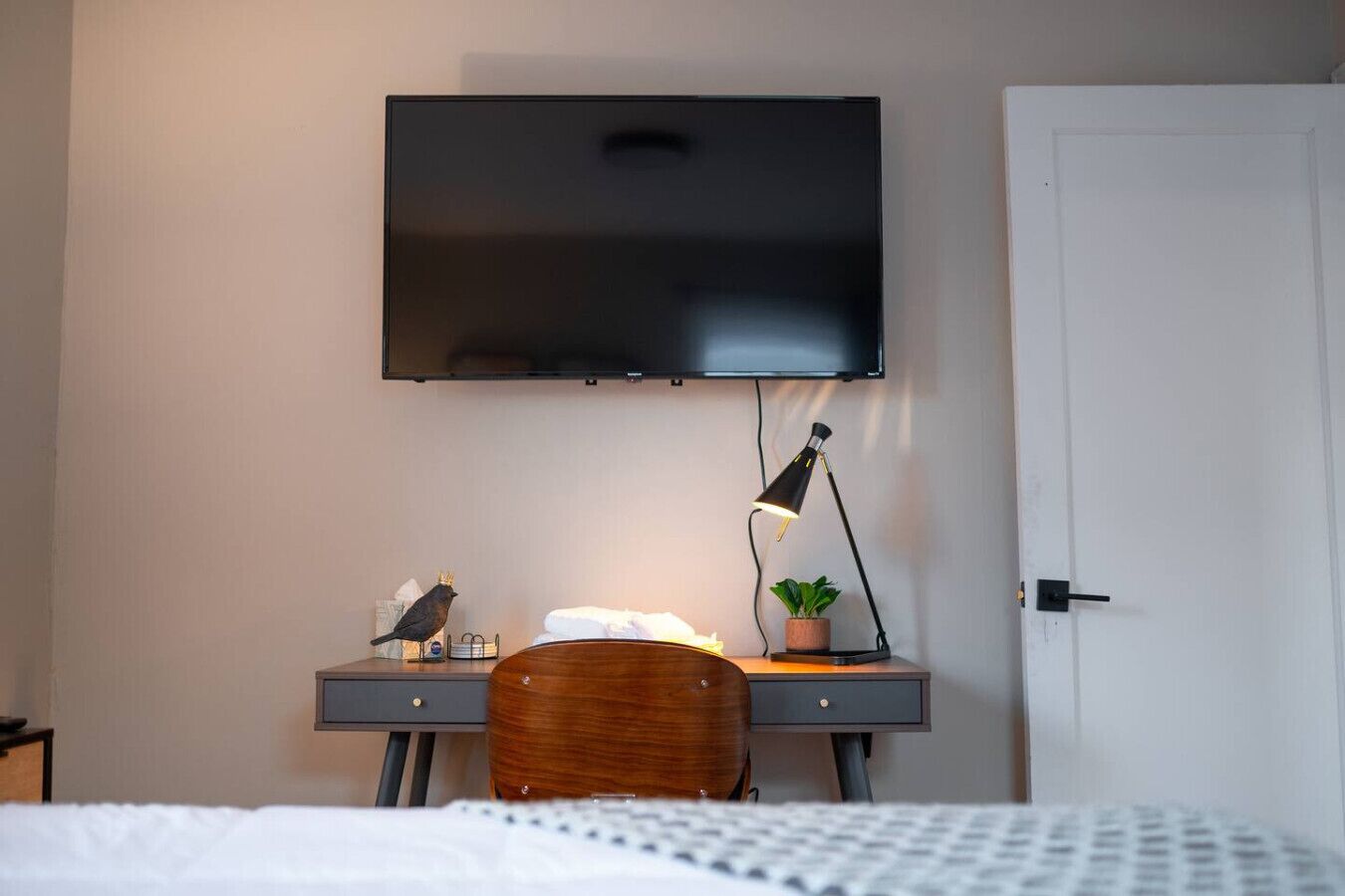 Une chambre d’hôtel comprenant un lit, un bureau avec un téléviseur à écran plat, une lampe, une chaise et une porte.