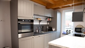 A modern kitchen with grey cabinets, a built-in oven, a sink, and a marble countertop. - Spacious Holiday Home in Oirschot Near Forest (Oirschot)