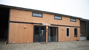 A modern building with a wooden facade, large glass doors, and multiple windows. - Spacious Holiday Home in Oirschot Near Forest (Oirschot)