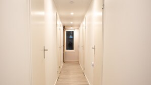 A long, narrow hallway with wooden flooring and white walls, leading to a door at the end. - Spacious Holiday Home in Oirschot Near Forest (Oirschot)