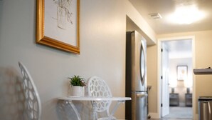 A modern kitchen with white cabinetry, a stainless steel refrigerator, and a white dining table with chairs. - Private Basement - Two King Beds and Hot Tub (Saint Charles)