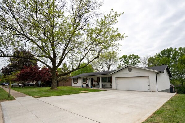 A single-story house with a garage, a covered porch, and a lawn.