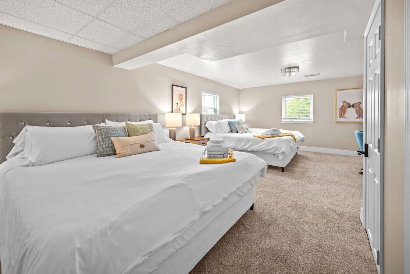 Habitación de hotel con dos camas, un ventanal grande y una lámpara en el techo.
