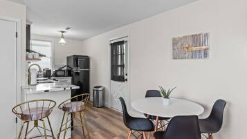 A compact kitchen with a refrigerator, sink, and modern bar stools.
