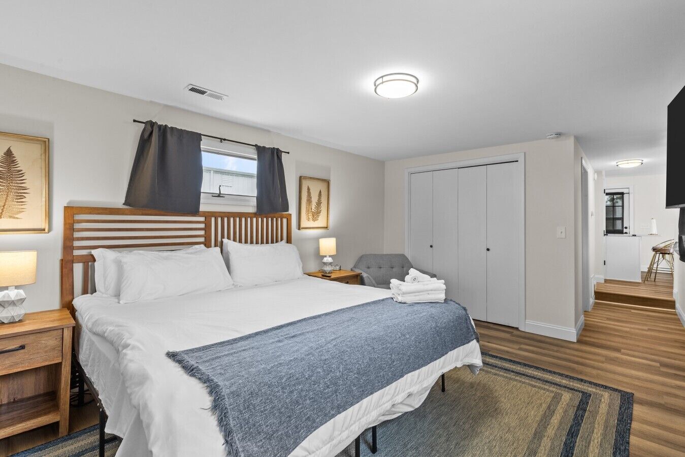 A hotel room with a bed, bedside tables, a chair, a wardrobe, and a television.