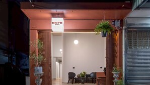 A hotel entrance with a sign reading "morn hotel," a reception desk, seating area, and potted plants.
