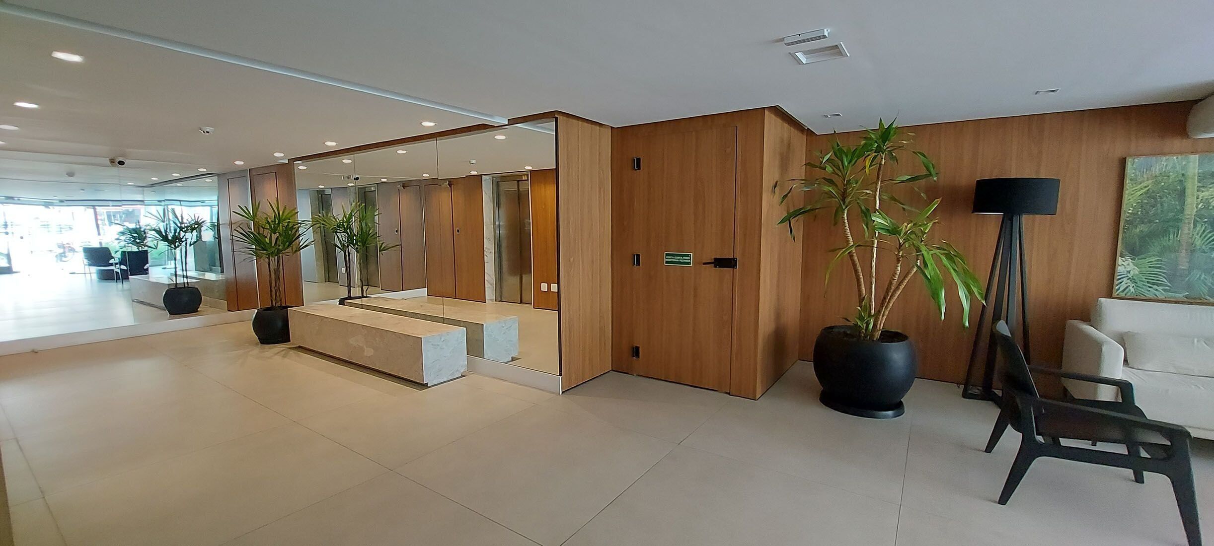 Una hall moderna di un hotel con una reception in legno, una scala e piante in vaso.