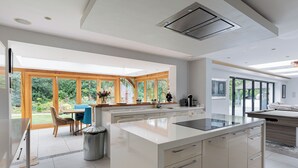 Una cocina moderna con una isla grande, ventanas de madera y vistas al jardín.