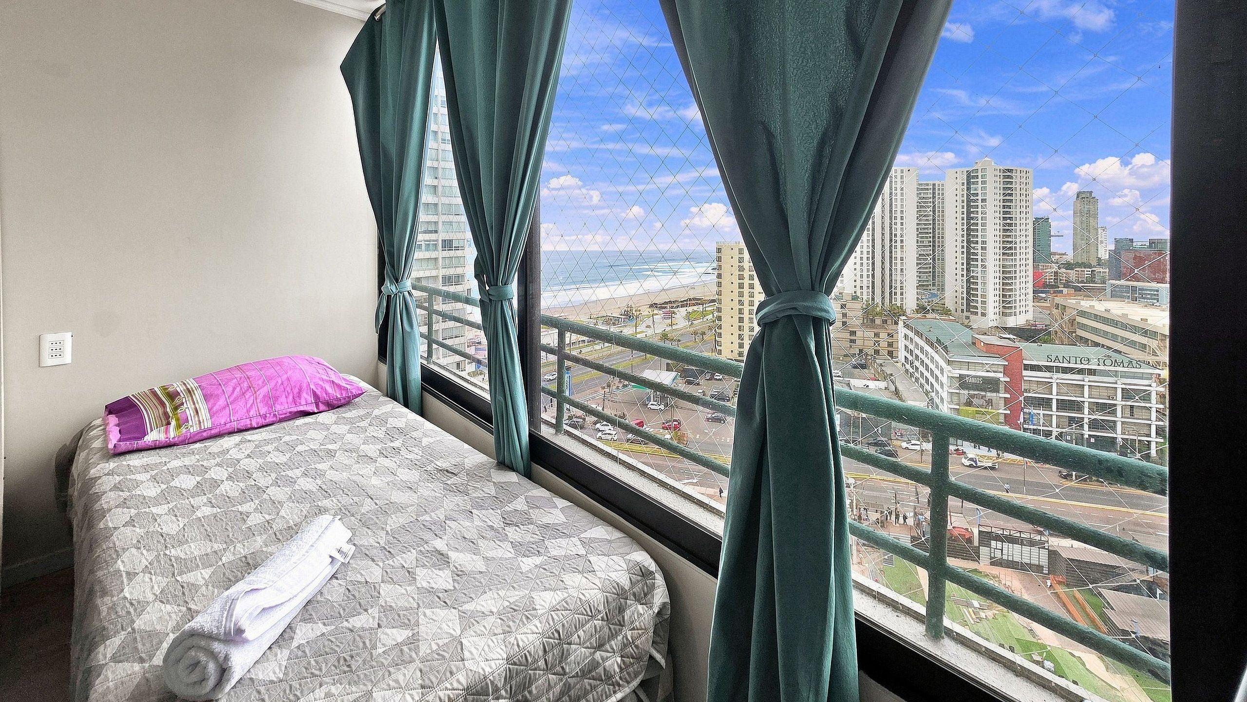 Une chambre d’hôtel avec un lit, une fenêtre avec des rideaux et une vue sur le paysage urbain.
