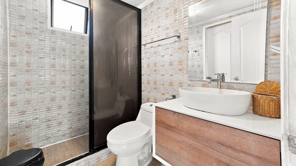 Un baño con inodoro, lavabo y cabina de ducha.
