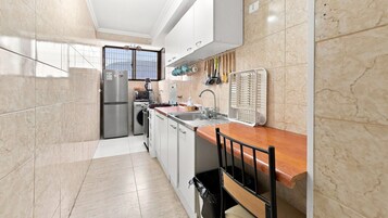 Cocina compacta con refrigerador, microondas, estufa, lavamanos y encimera de madera.