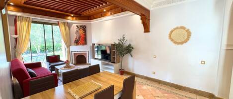 A dining area with a wooden table and chairs, a fireplace, and a TV.