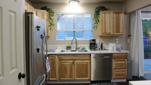 A kitchen with wooden cabinets, a stainless steel refrigerator, a sink, and a window with blinds. - Kelso Pitstop (Kelso)