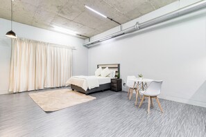 A modern bedroom with a bed, bedside table, and a desk with chairs.