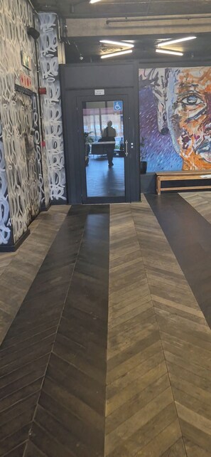 A hallway with a patterned floor leading to a door with a wheelchair accessibility sign.