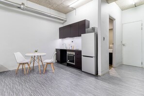 A modern kitchen with a dining area, including a white table with chairs, a microwave, oven, and cabinets.