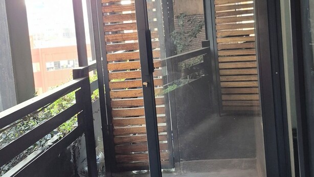 Un balcón con puerta de vidrio que da a una terraza de madera.