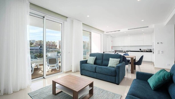 A modern apartment with a living area, kitchen, and balcony.