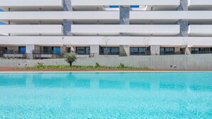 Un hôtel moderne doté d’une piscine, de nombreux balcons et d’une façade en béton.