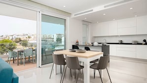 Un appartement moderne comprenant un coin repas, une cuisine et un balcon avec vue sur la ville.