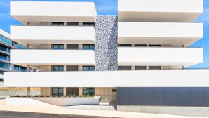 A modern multi-story building with a flat facade, large windows, and a distinctive patterned wall.