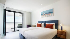 A modern bedroom with a large bed, a desk, and a chair.