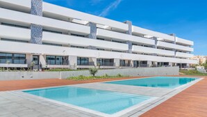 A modern building with a swimming pool and a wooden deck.
