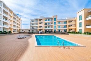 Ein modernes Hotel mit großem Außenpool, mehreren Balkonen und einer gepflegten Terrasse.