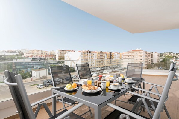 Ein Balkon mit einem für das Frühstück gedeckten Tisch, mit Blick auf ein Wohngebiet.
