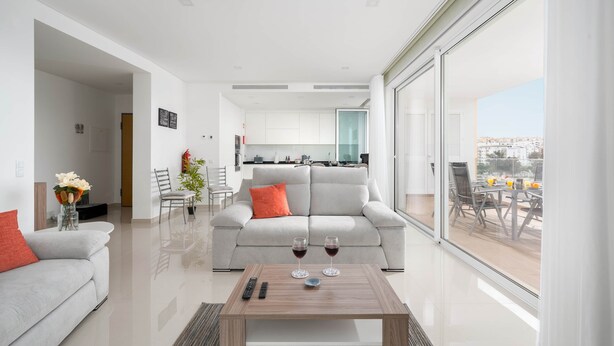 A modern living room with a sofa, a coffee table with two wine glasses, and a view of the city through large windows. - CourtView Modern Lagos Apartment (Lagos)