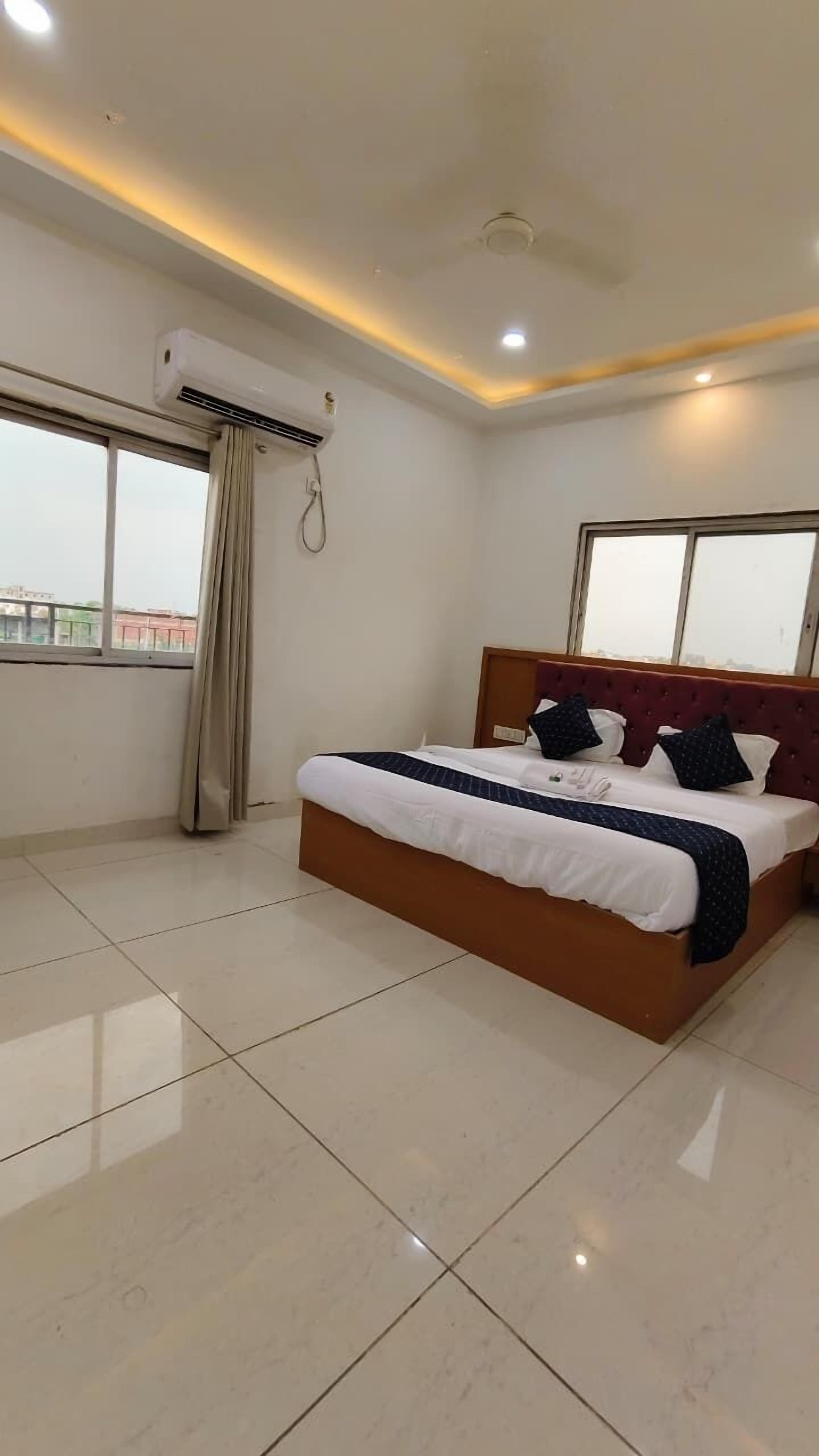 Une chambre d’hôtel dotée d’un grand lit, d’un ventilateur de plafond, d’un appareil de climatisation et offrant une vue sur la ville par les fenêtres.