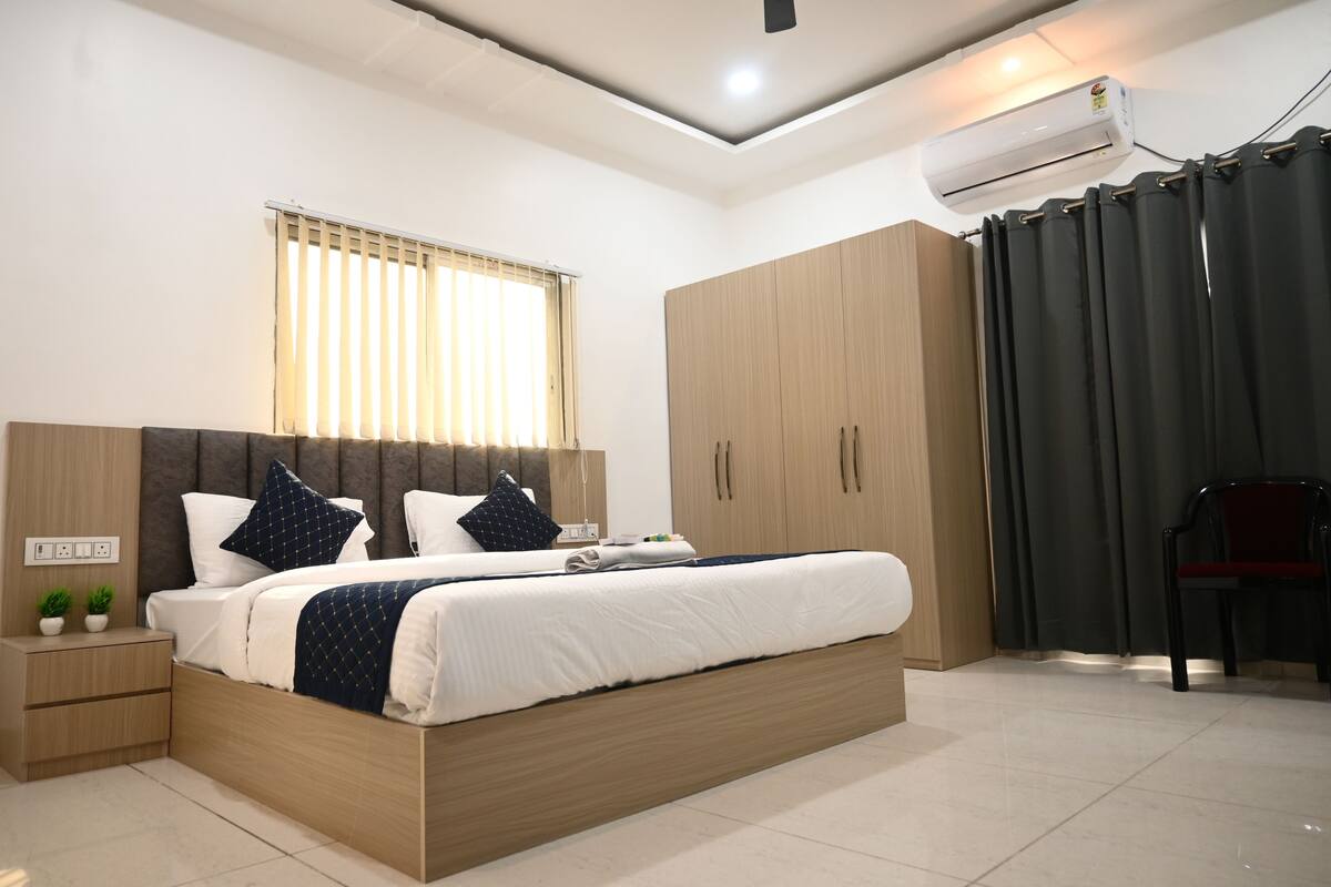 A modern bedroom with a large bed, wooden wardrobe, and an air conditioning unit.