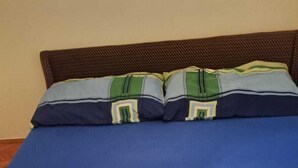Una cama con colchón azul y cabecera trenzada marrón.