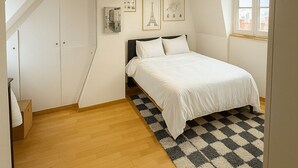 Ett sovrum med en säng, en rutig matta och inramade tavlor på väggen.