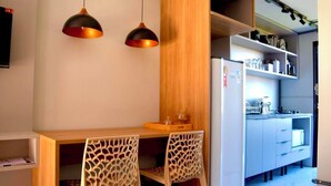 Een kleine keuken met een houten tafel, twee stoelen en hanglampen.