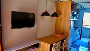 Een kleine keuken met een houten werkblad, twee hanglampen en een ingebouwde televisie.