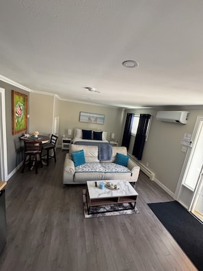 A compact living space with a sofa, a dining table, and a bed.