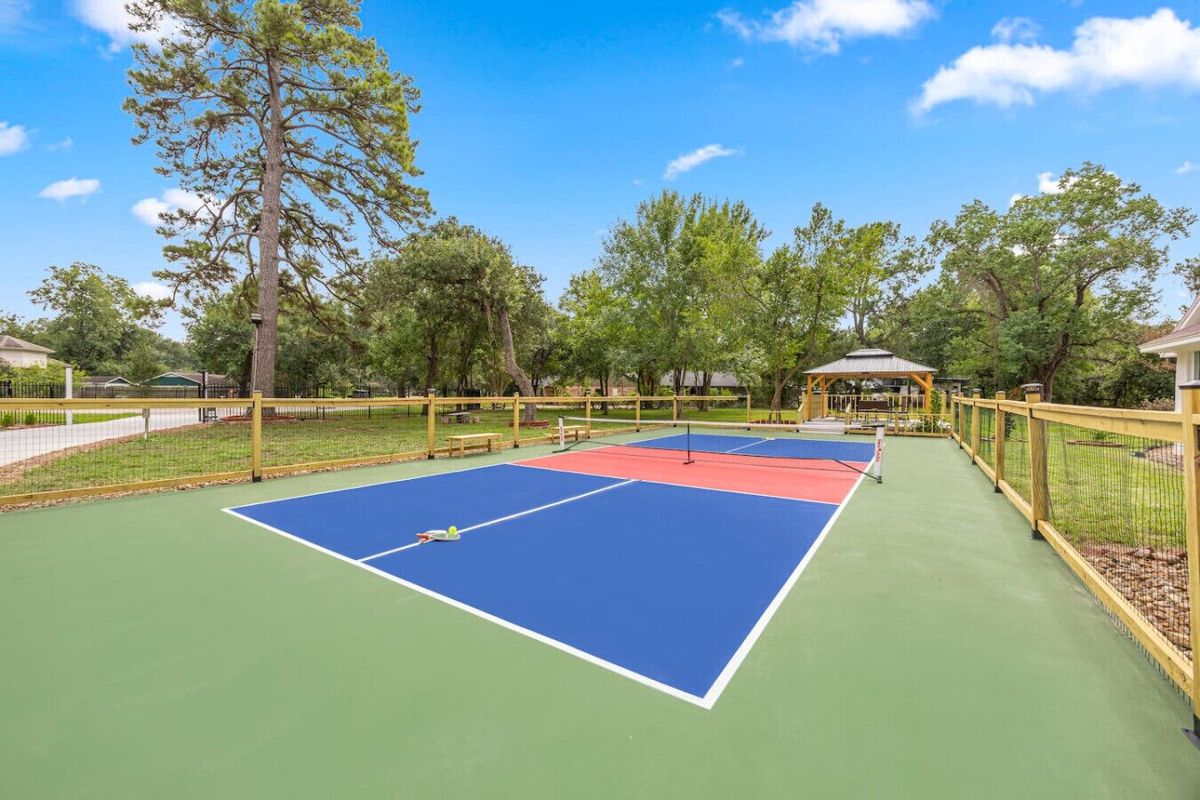 Een tennisterrein buiten, met een paviljoen op de achtergrond.