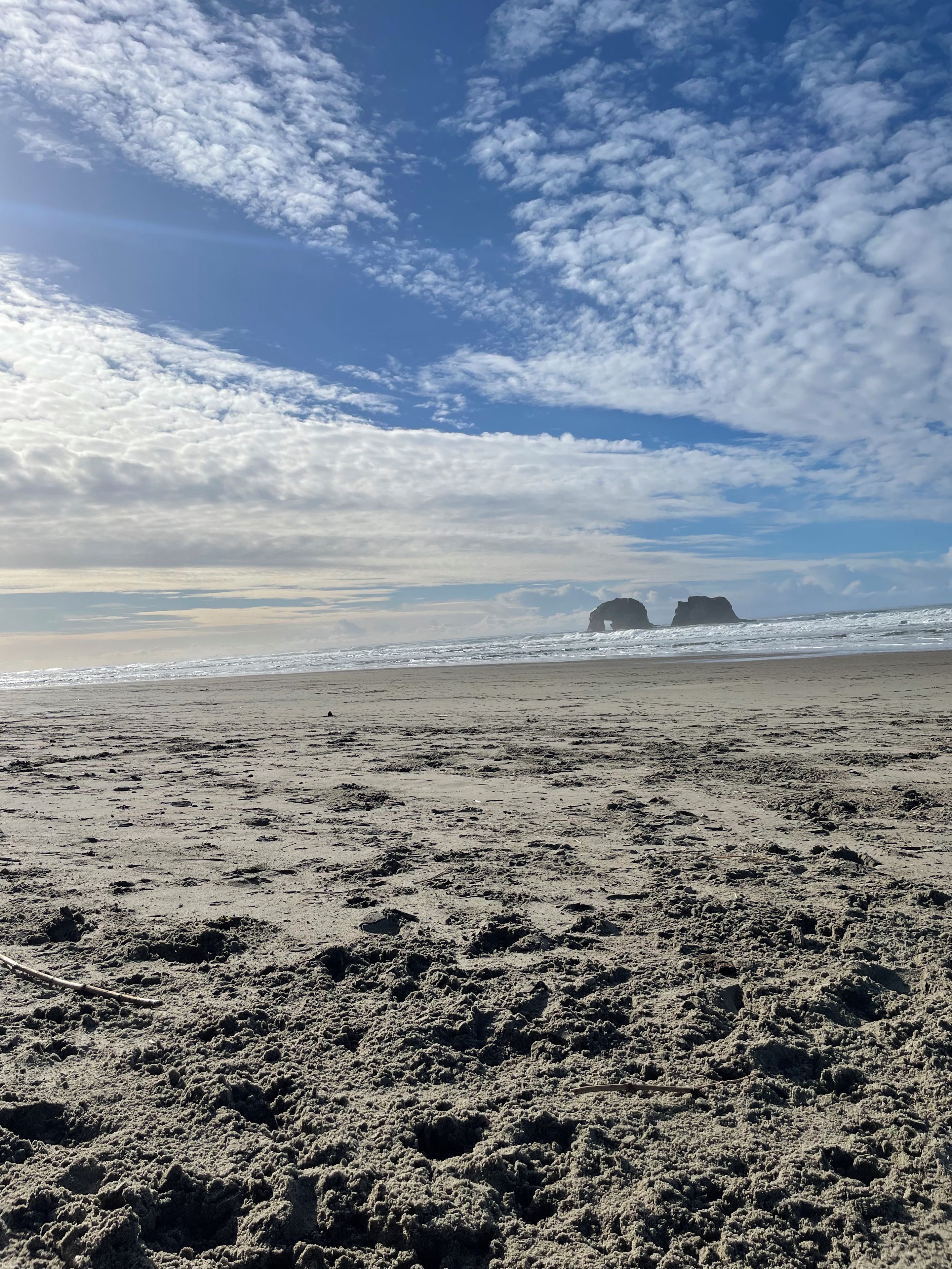 A beach with a sandy shore, waves, and a clear sky with clouds.