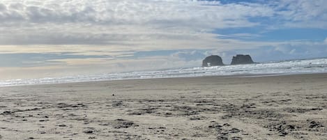 A beach with a sandy shore, waves, and a clear sky with clouds.